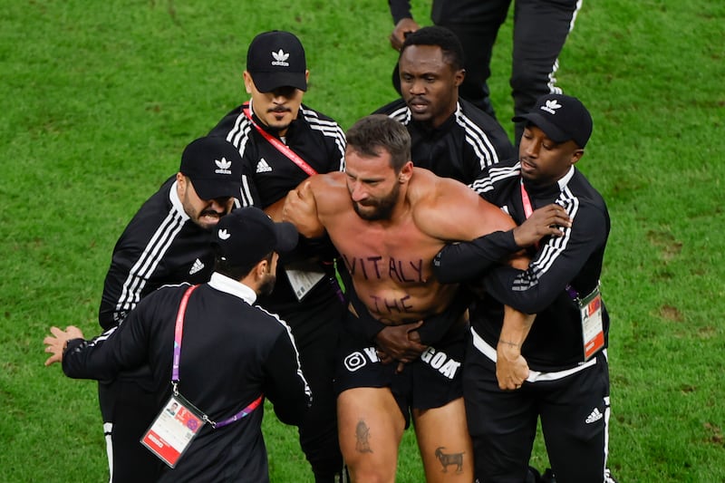 Asistentes sacan a un hincha que invadió el campo en el partido de Países Bajos y Argentina