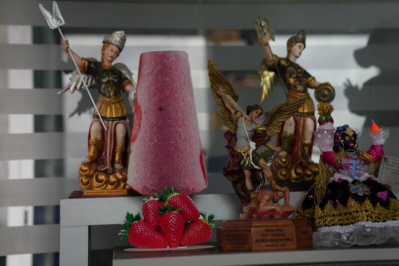 Una silueta de paleta en cartón adorna un estante junto a una figura del arcángel san Miguel, patrón de Salcedo, en Ecuador, el jueves 28 de noviembre de 2024, durante una sucesión de apagones provocados por una prolongada sequía.  (AP Foto/Dolores Ochoa)