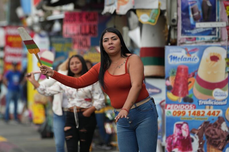 Una vendedora mueve un cartel con forma de paleta para atraer a posibles clientes en Salcedo, Ecuador, el jueves 28 de noviembre de 2024 en medio de una oleada de cortes de luz provocada por una persistente sequía. (AP Foto/Dolores Ochoa)